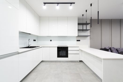 Elegant white minimalist kitchen featuring sleek cabinetry and modern lighting.
