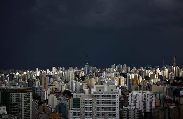 A striking view of Sao Paulo's urban skyline beneath dark storm clouds, showcasing the city's architectural diversity.