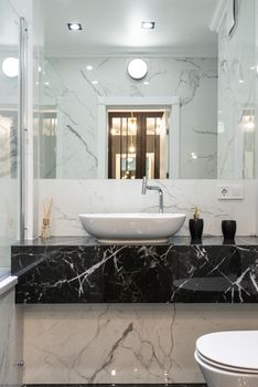 Contemporary bathroom with marble accents, featuring a minimalist sink and black countertop.