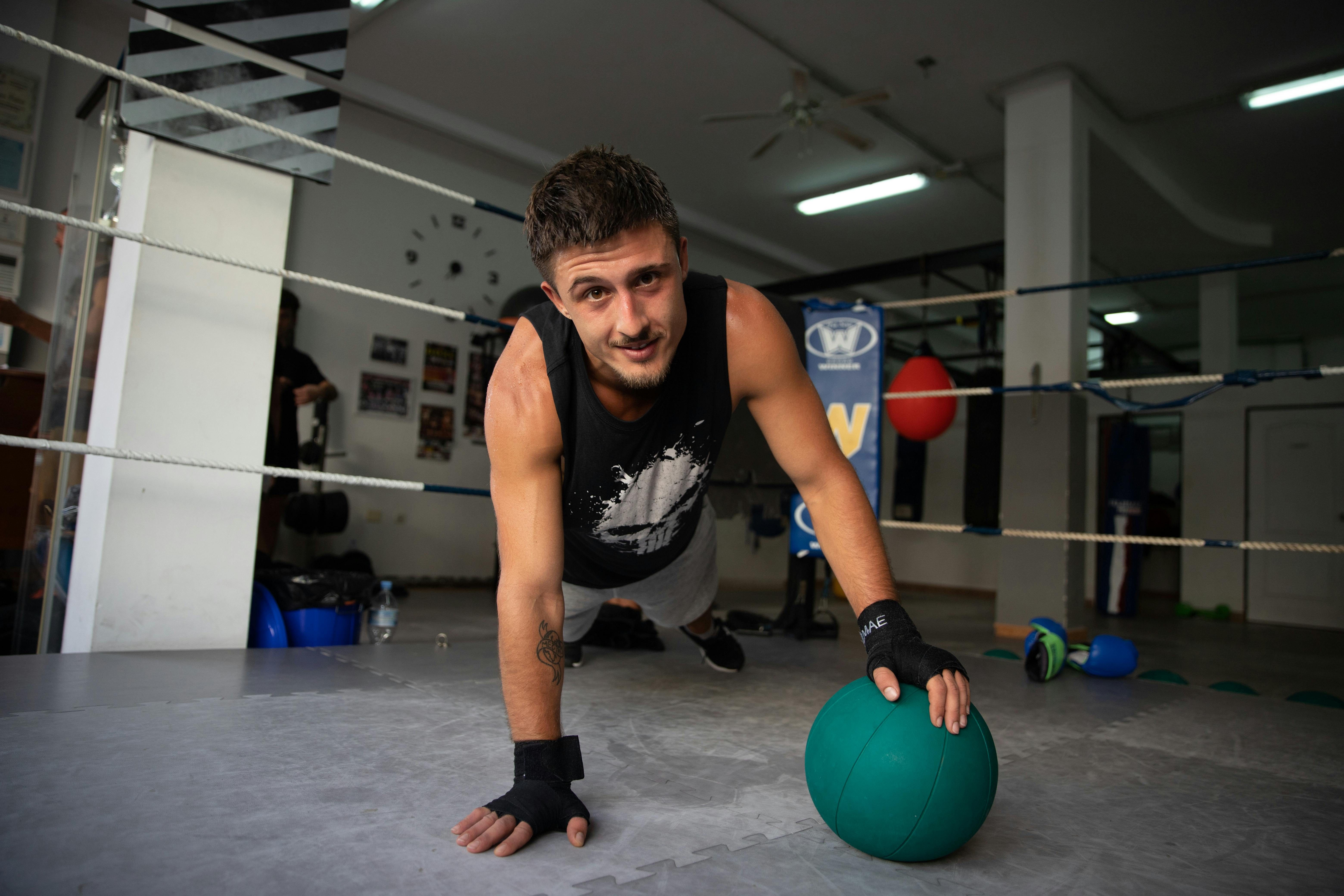 man in black tank top and black shorts holding blue ball