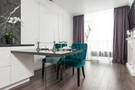 Elegant wineglasses with plates and candlesticks served on table near comfortable velour chairs in modern apartment with white furniture and walls