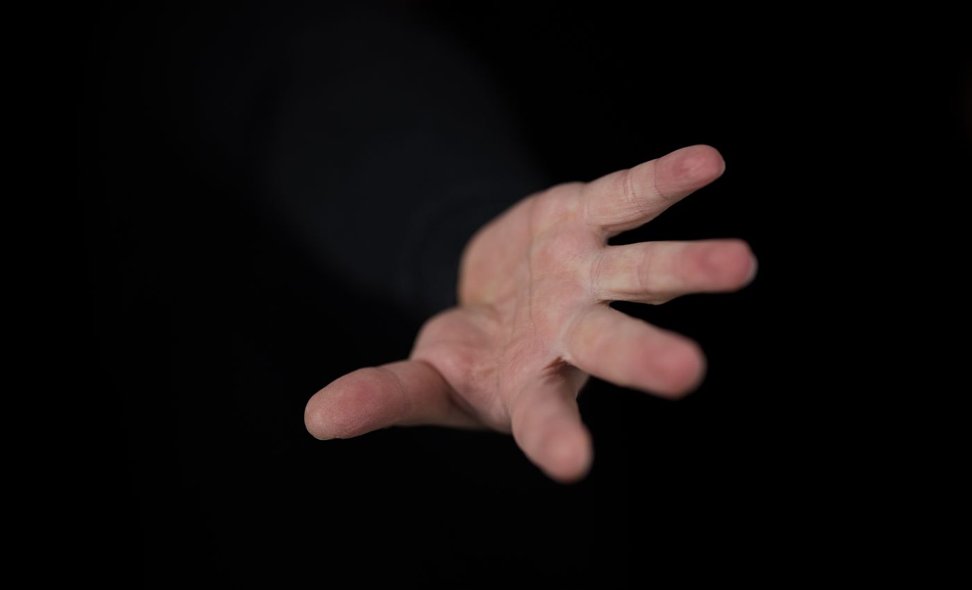 An open hand reaching out of darkness. Photo by Engin Akyurt on Pexels.