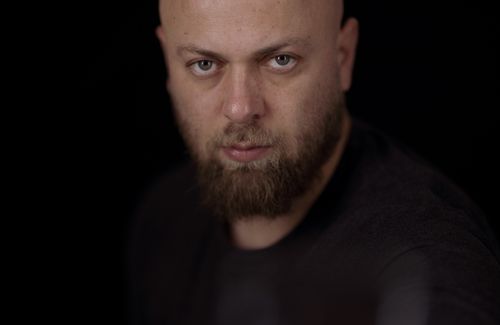 Free Close-up portrait of a bearded man with an intense gaze against a dark background. Stock Photo