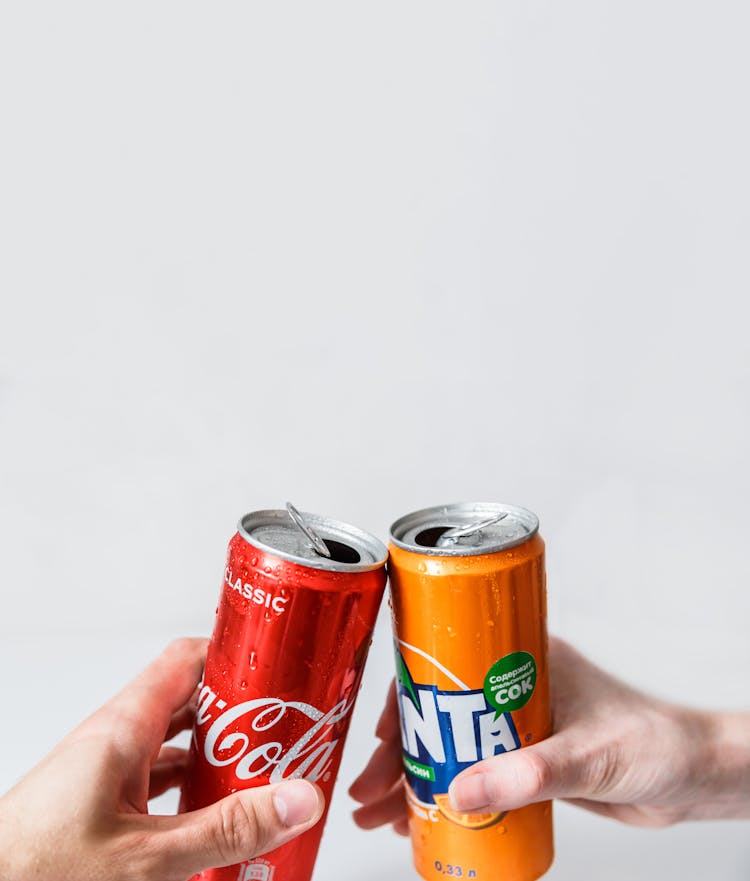 People Holding Canned Softdrinks