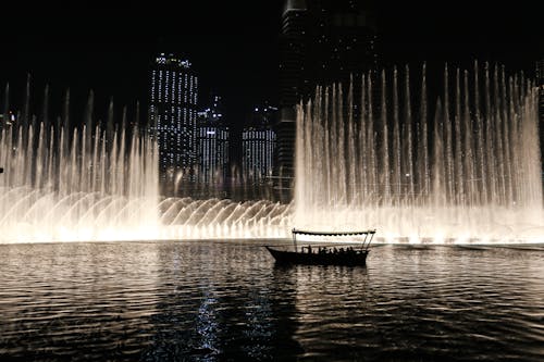 Silhouette of a Boat on a Body of Water With Fountain