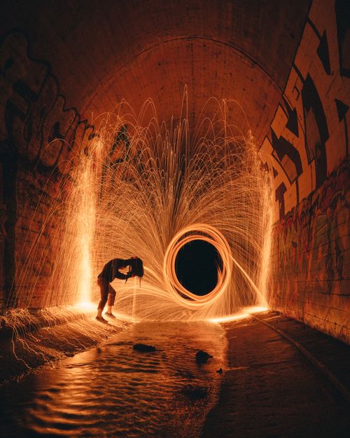 Free Side view of anonymous male hiding behind backpack against bright freeze light in sewer tunnel in evening Stock Photo