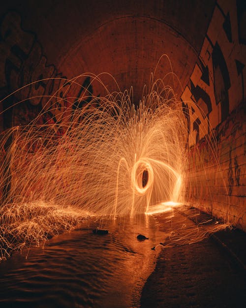 Shiny freeze light in sewer tunnel with rippled water between rough walls with letters at dusk