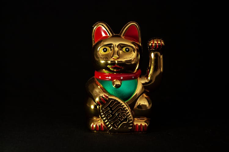 A Gold Lucky Cat On Black Surface