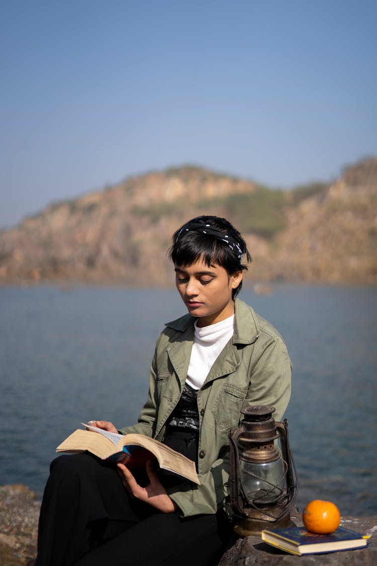 Woman Reading A Book By The Lake