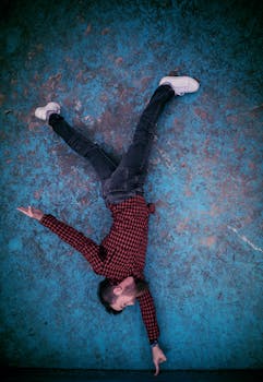 俯视图中，一名身穿红色格子衬衫的男子躺在蓝色纹理背景上