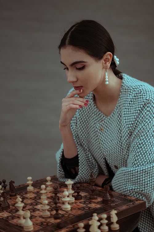 Focused woman thinking about next move and playing chess · Free Stock Photo