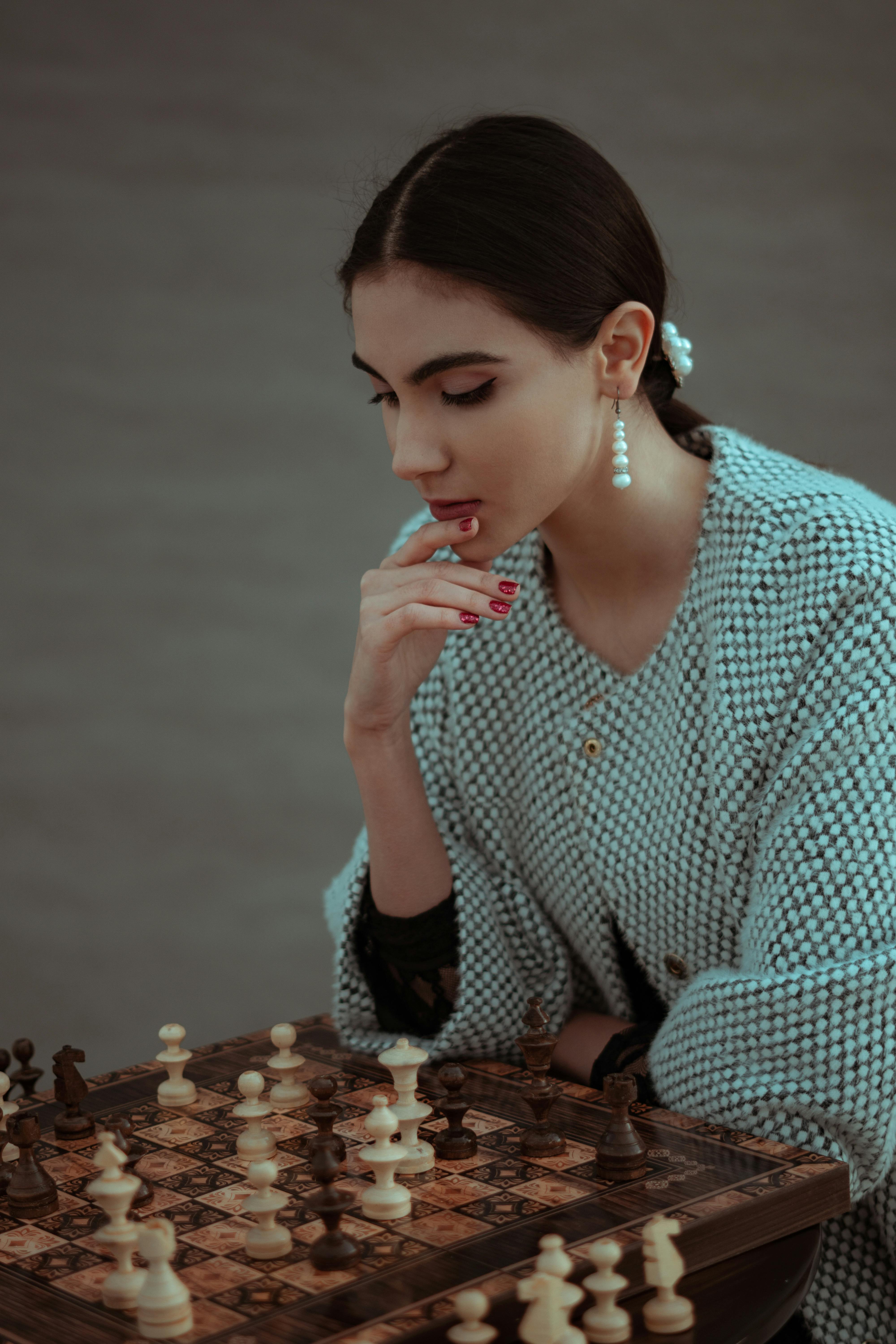 Woman playing chess thinking of next move Stock Photo - Alamy