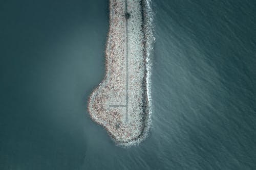 Aerial view of stone breakwater in rippling water of turquoise sea on sunny day