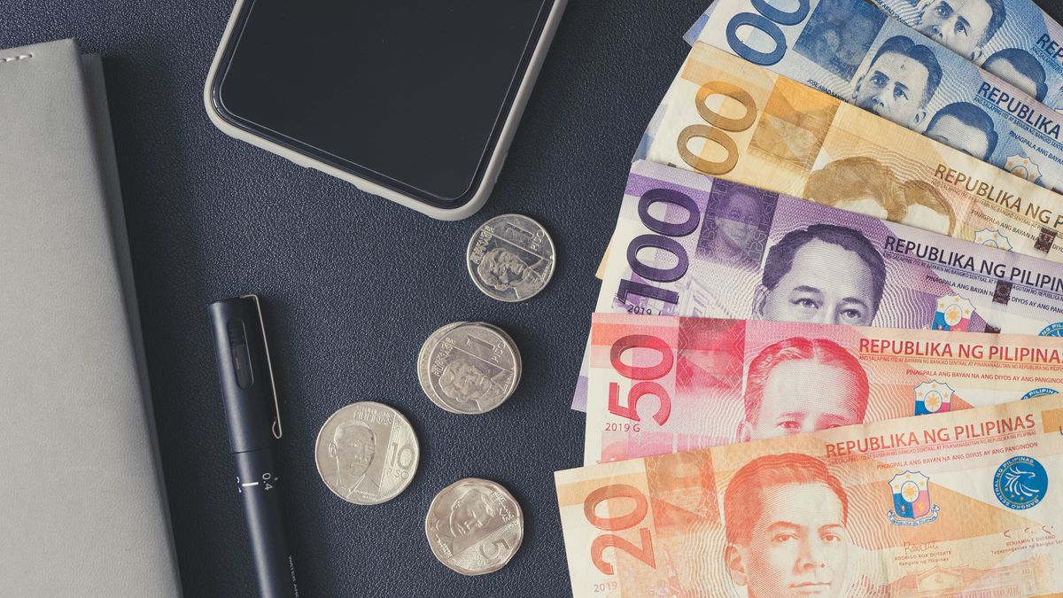 Flat lay of Philippine peso bills, coins, smartphone, and notebook. Ideal for financial themes.