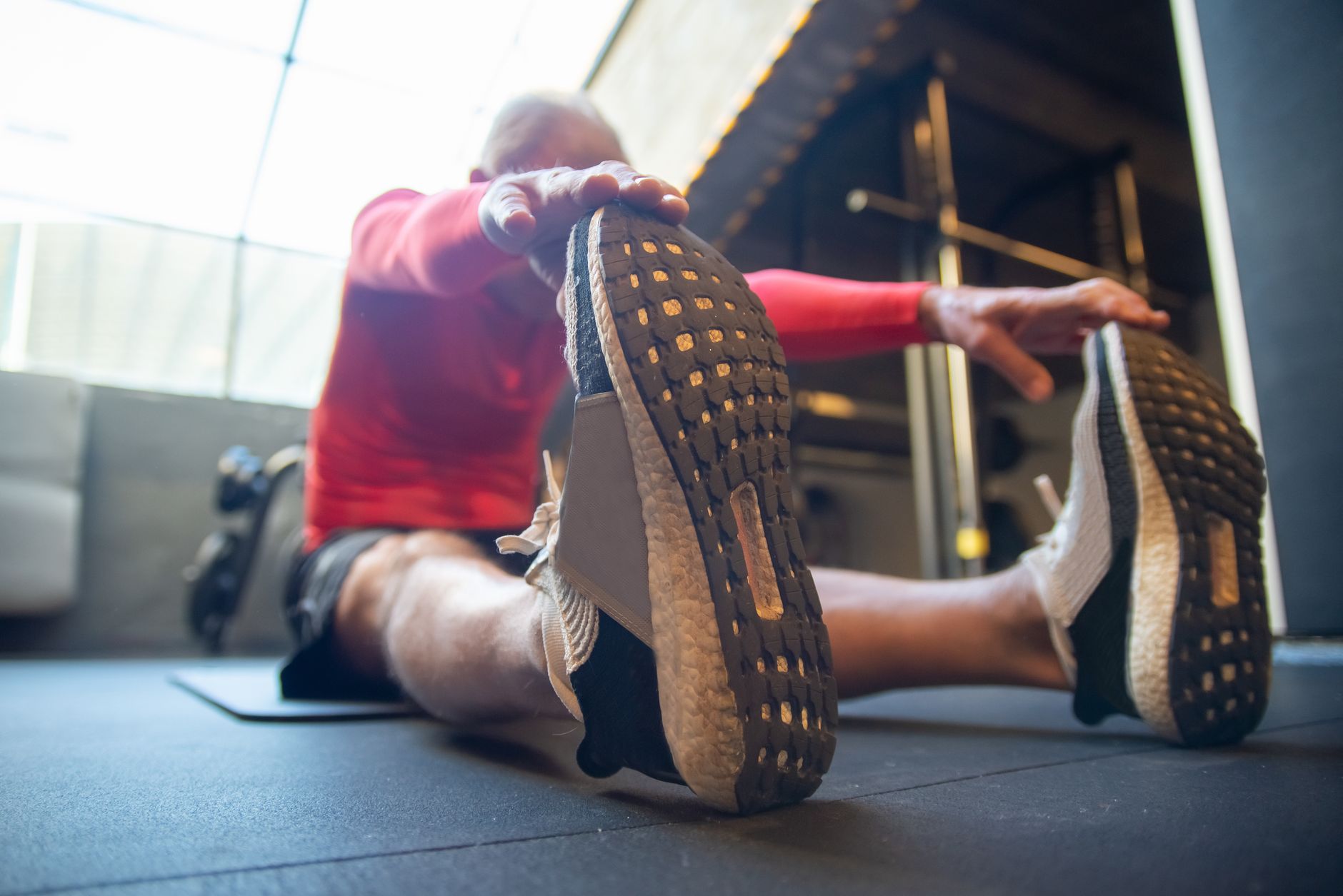 Senior man stretching in a modern gym, promoting fitness and health.