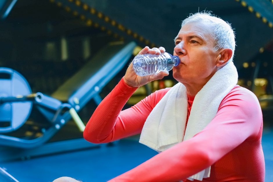 Pratiquant qui boit de l'eau pendant le repos entre deux séries en salle de musculation