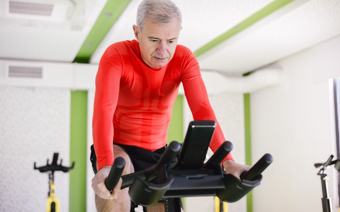 Older man pedalling a stationary exercise bike indoors