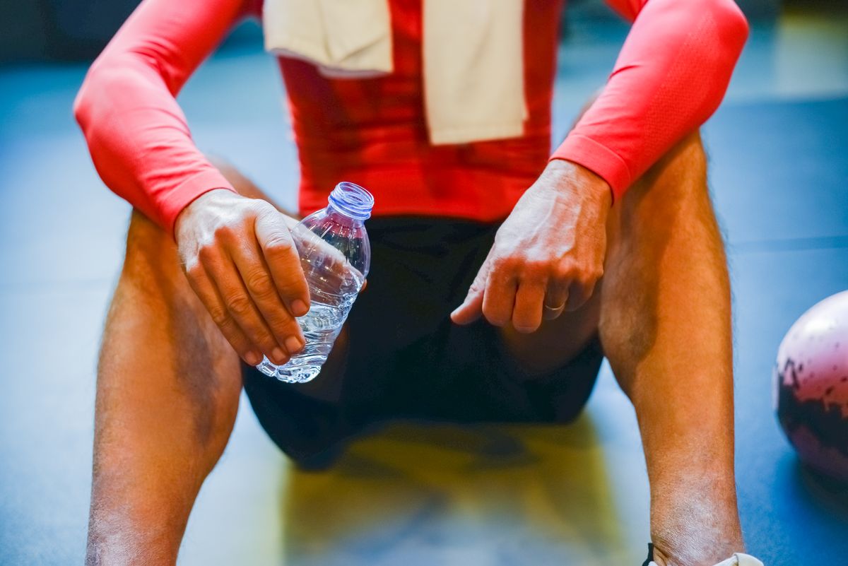 Person hält eine Wasserflasche im Fitnessstudio