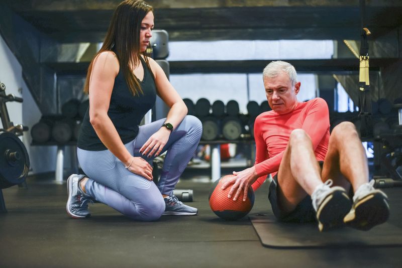 Entrenador personal guiando a un cliente en un ejercicio de core