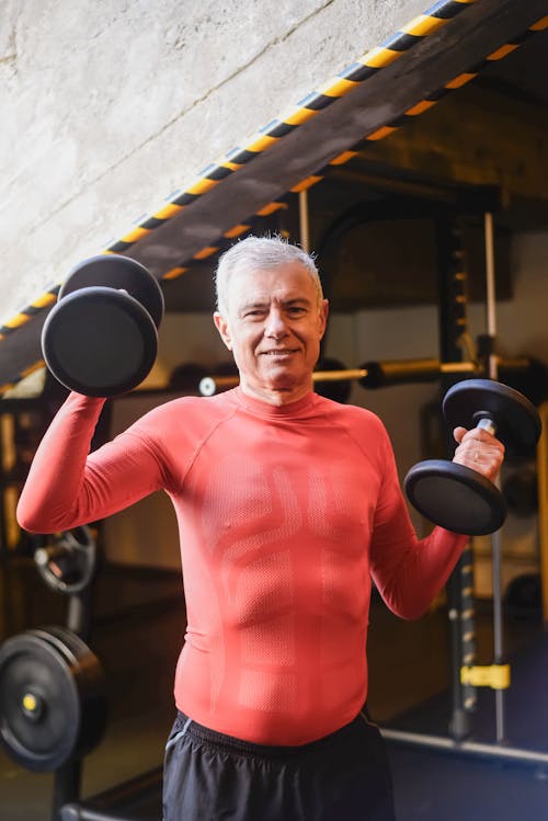 Free Smiling Elderly Man Lifting Two Heavy Dumbbells Stock Photo