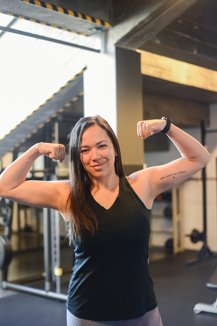 Confident Woman In Black Tank Top Flexing Her Biceps