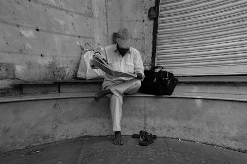 Monochrome Photo of a Person Reading Newspaper