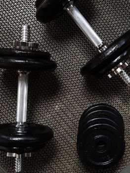 Detailed view of black dumbbells on textured surface, perfect for fitness themes.