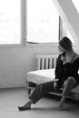 Black and white feminine female in unbuttoned shirt sitting on cozy bed near window