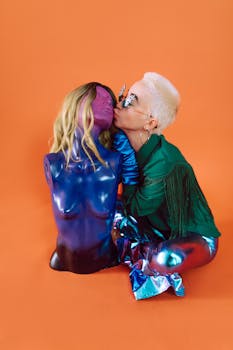 Artistic portrait featuring a person interacting with a colorful mannequin against an orange backdrop.