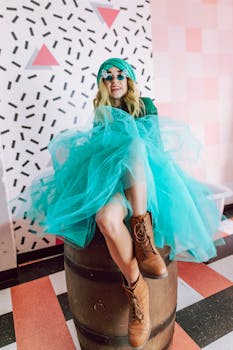 Woman in teal dress and boots posing indoors with playful decor.
