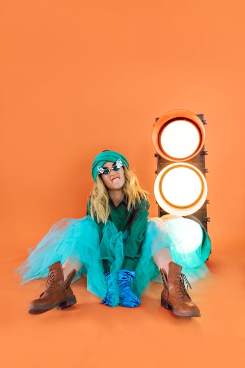 Woman in Teal Long Sleeve Shirt and Brown Pants Sitting on Brown Wooden Seat