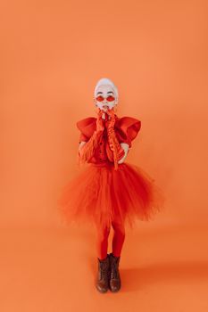 A stylish woman in orange attire posing against a matching background, emphasizing bold fashion.