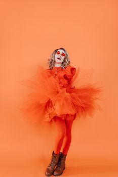 A colorful portrait of a young woman in a vibrant orange costume, dancing.