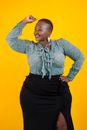 Cheerful black overweight woman with raised arm in studio