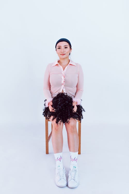 A Woman Sitting while Holding a Curly Wig