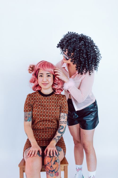 Free Two women posing with vibrant curly and pink hair, showcasing modern fashion and hairstyle trends. Stock Photo