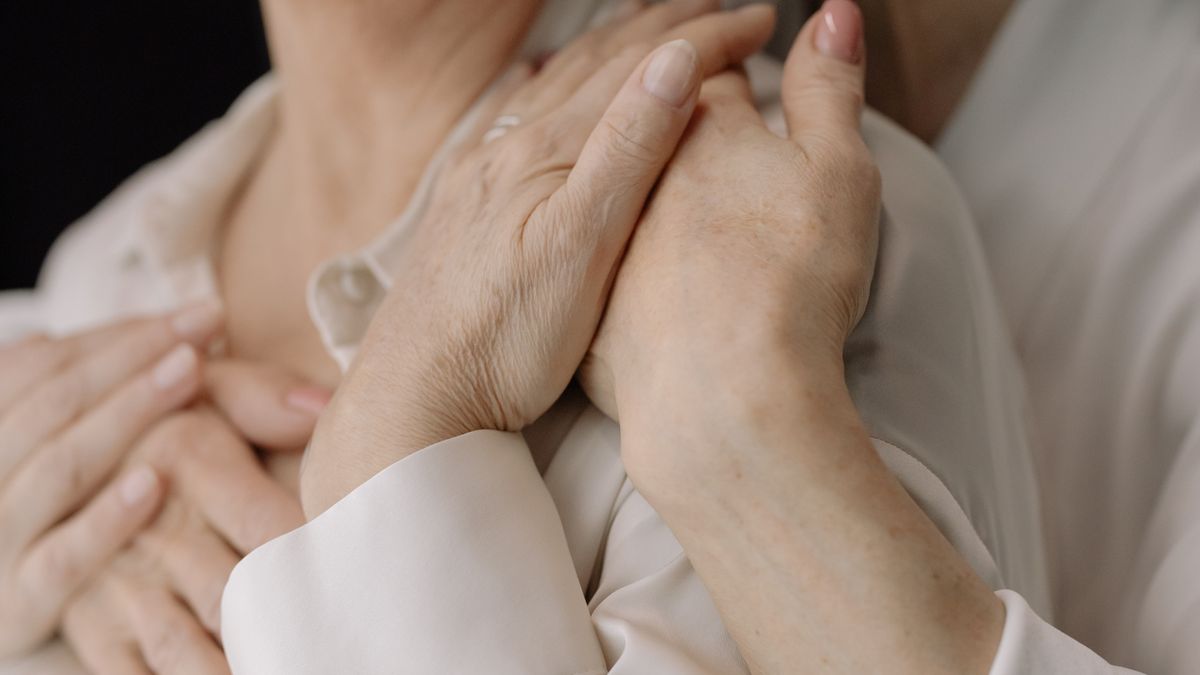 高齢の女性の手を、もう一人が両手で包んでいる