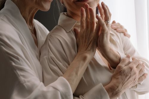 Free Close-up of two mature women embracing, showcasing friendship and intimacy, both wearing white blouses. Stock Photo