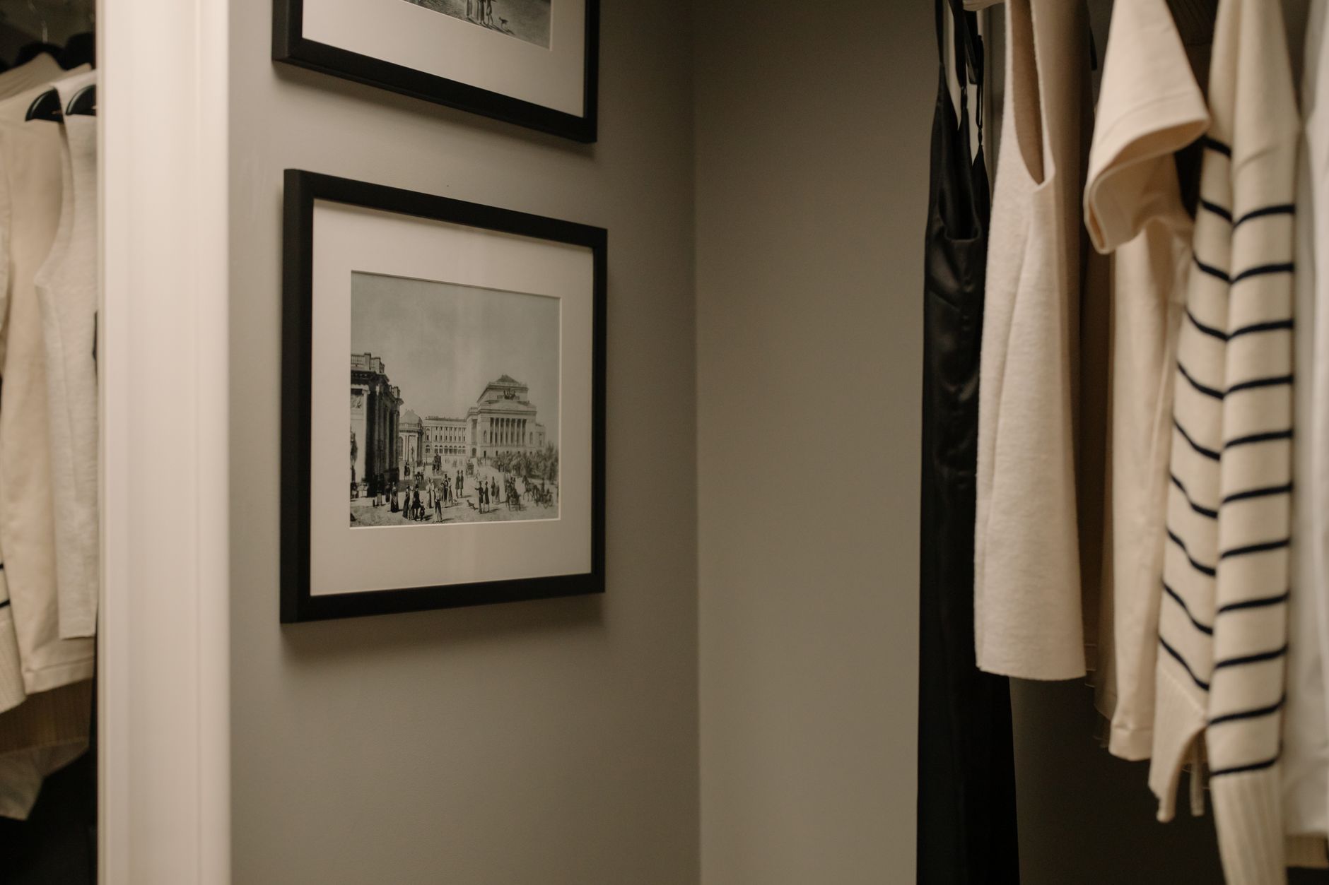 minimalist closet organization for cozy homes A well-organized closet with hanging clothes and vintage framed photographs for a modern minimalist look.