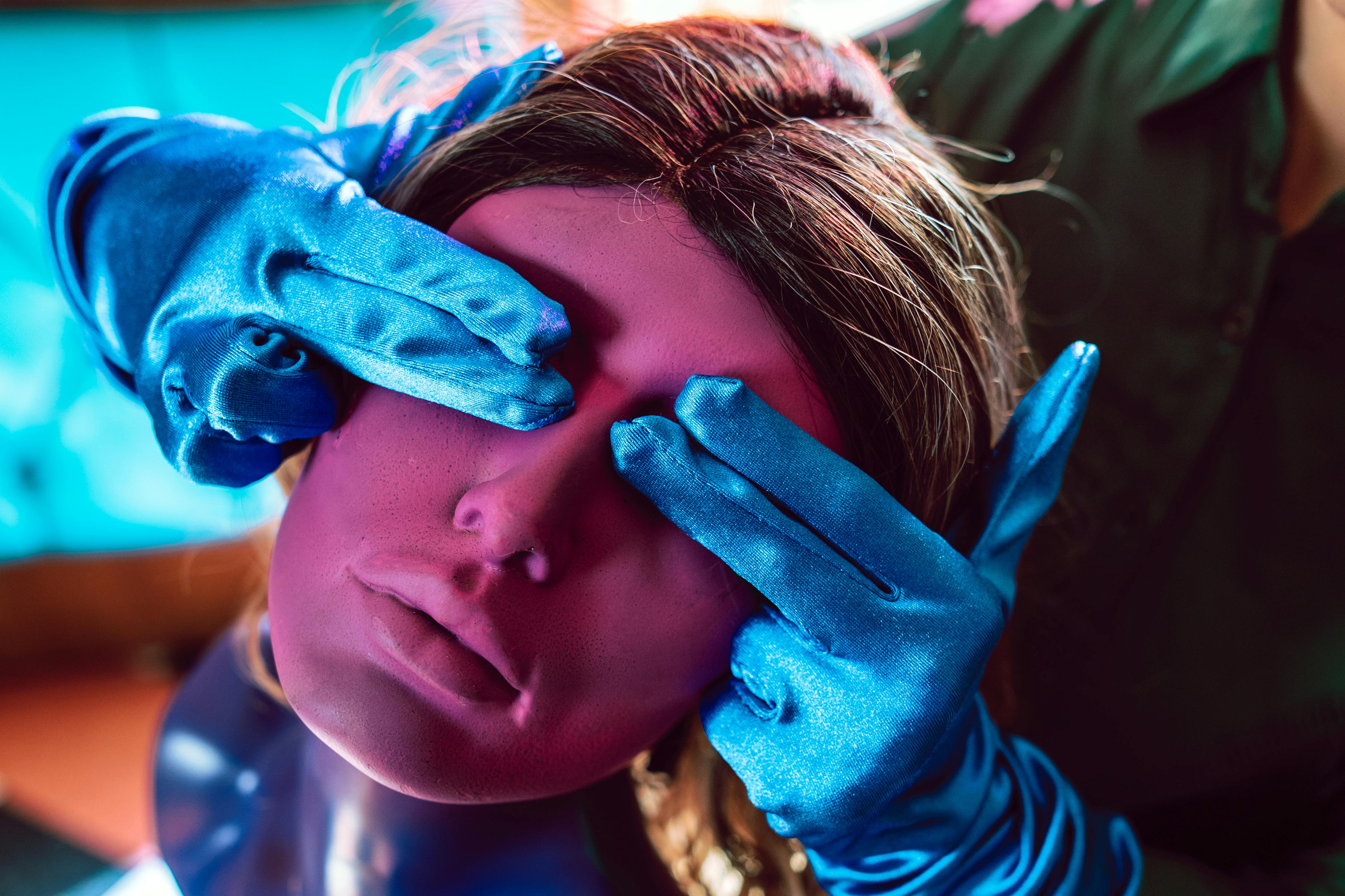 girl in blue and white polka dot shirt covering her face with blue rose