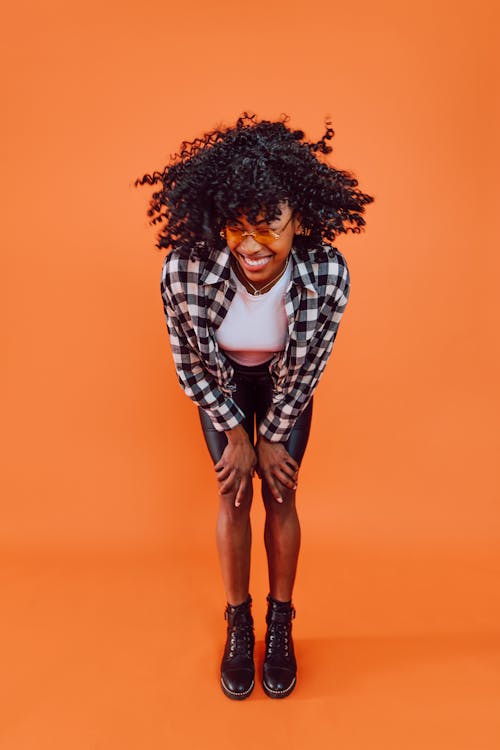 Woman in Black Plaid Long Sleeve Shirt Smiling and Holding Her Knees