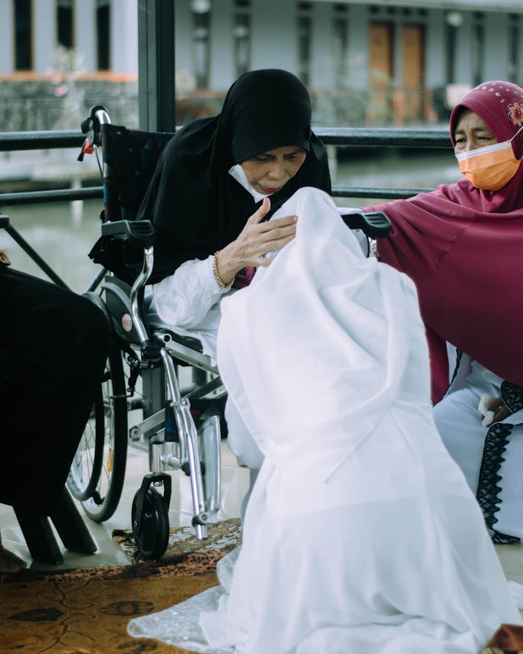 Woman In White Hijab Dress Kneeling And Showing Respect To Older People