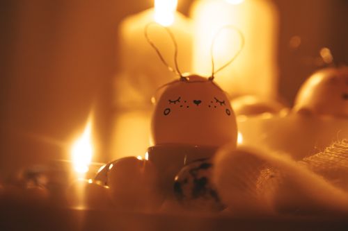 Free Cozy Easter scene with a decorated bunny egg and candlelight warmth. Stock Photo