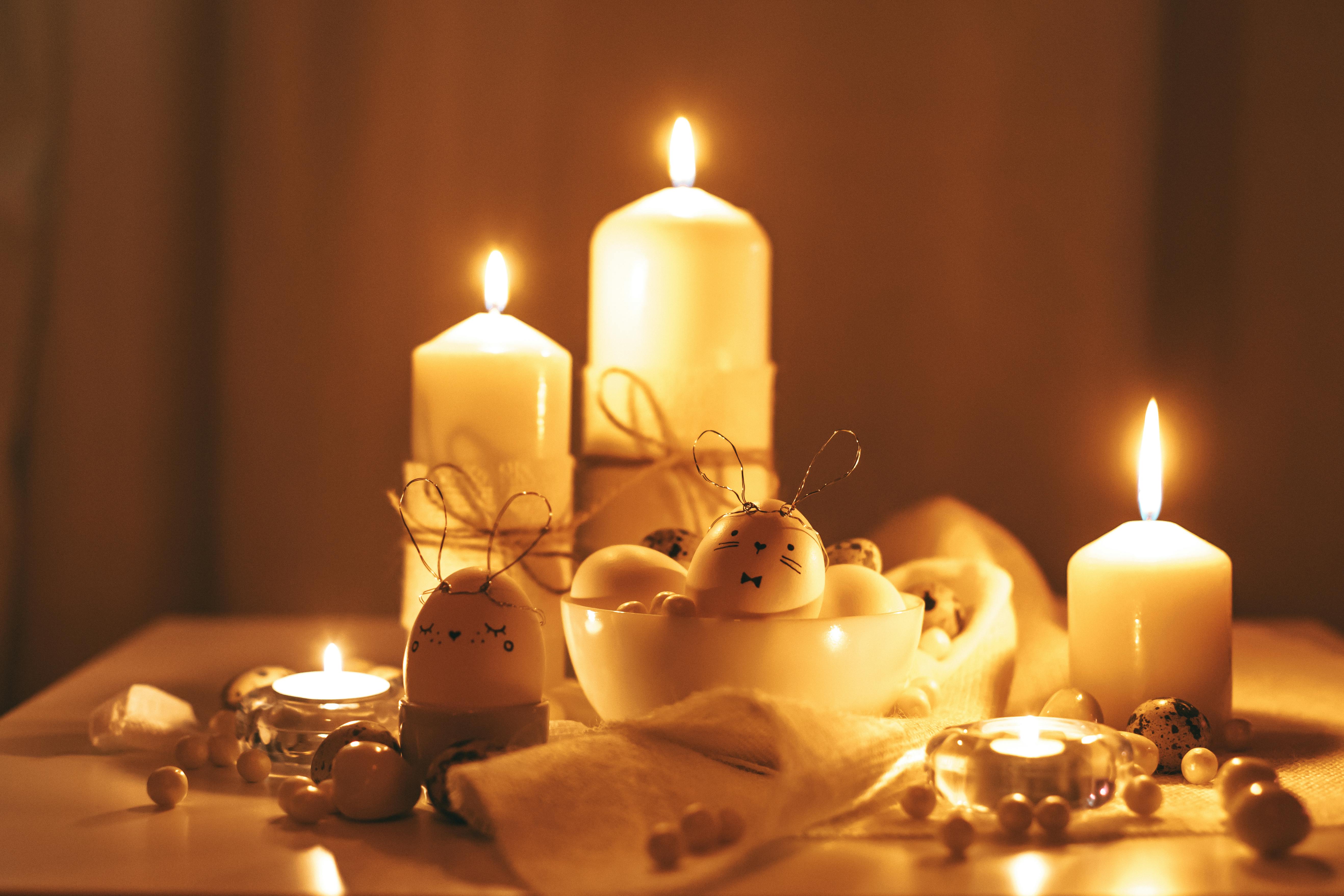 lighted candles and painted eggs on golden background