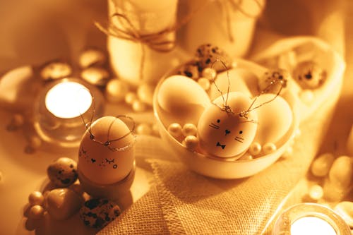 White Lighted Candles And Painted Eggs On Table
