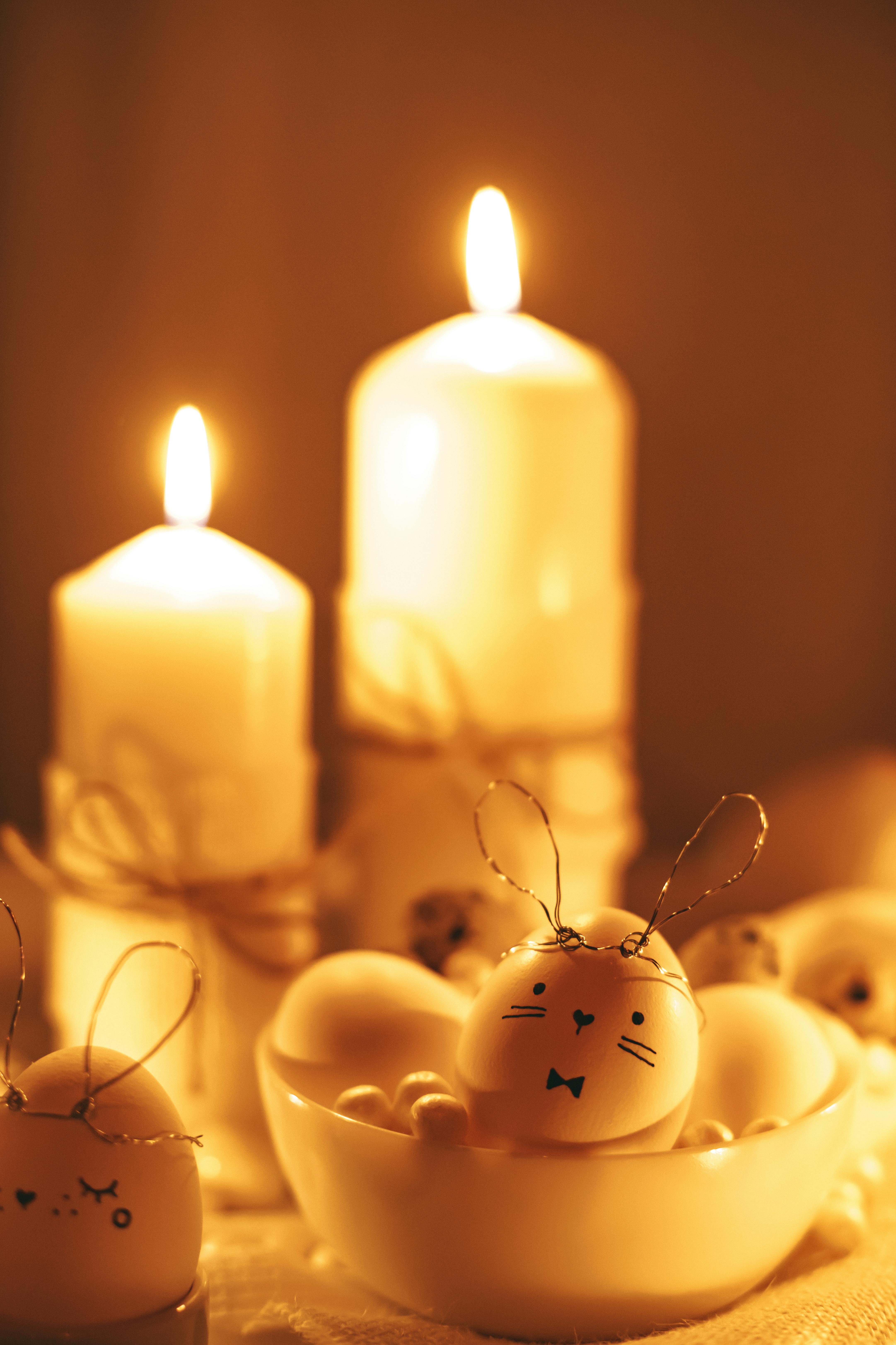 white lighted candles and painted eggs on table