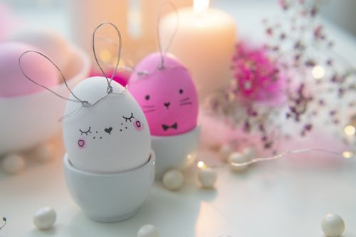 Free Decorated Easter eggs styled as cute bunnies alongside holiday candles. Stock Photo