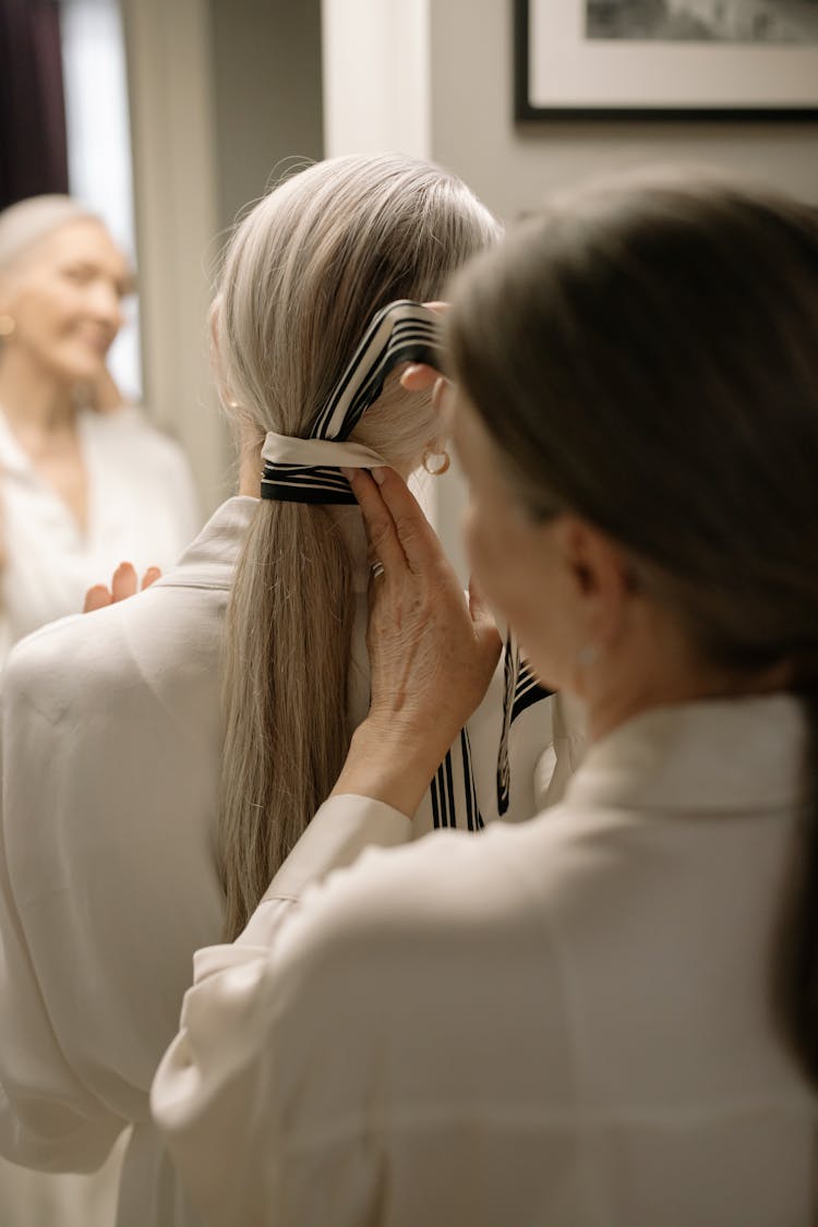 A Woman Tying A Person's Hair