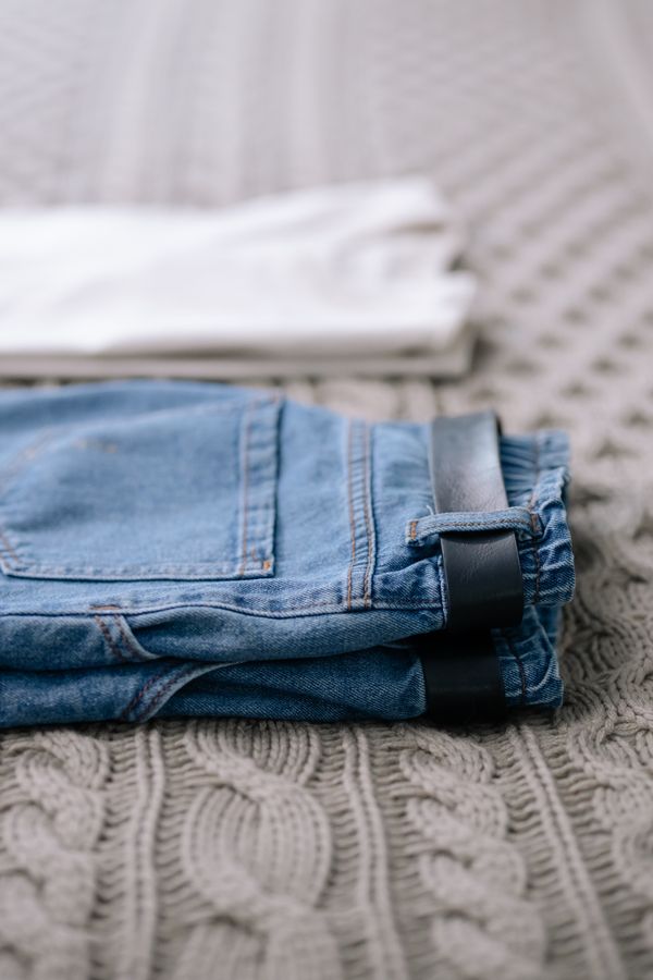Folded jeans on a knit blanket by cottonbro studio on Pexels