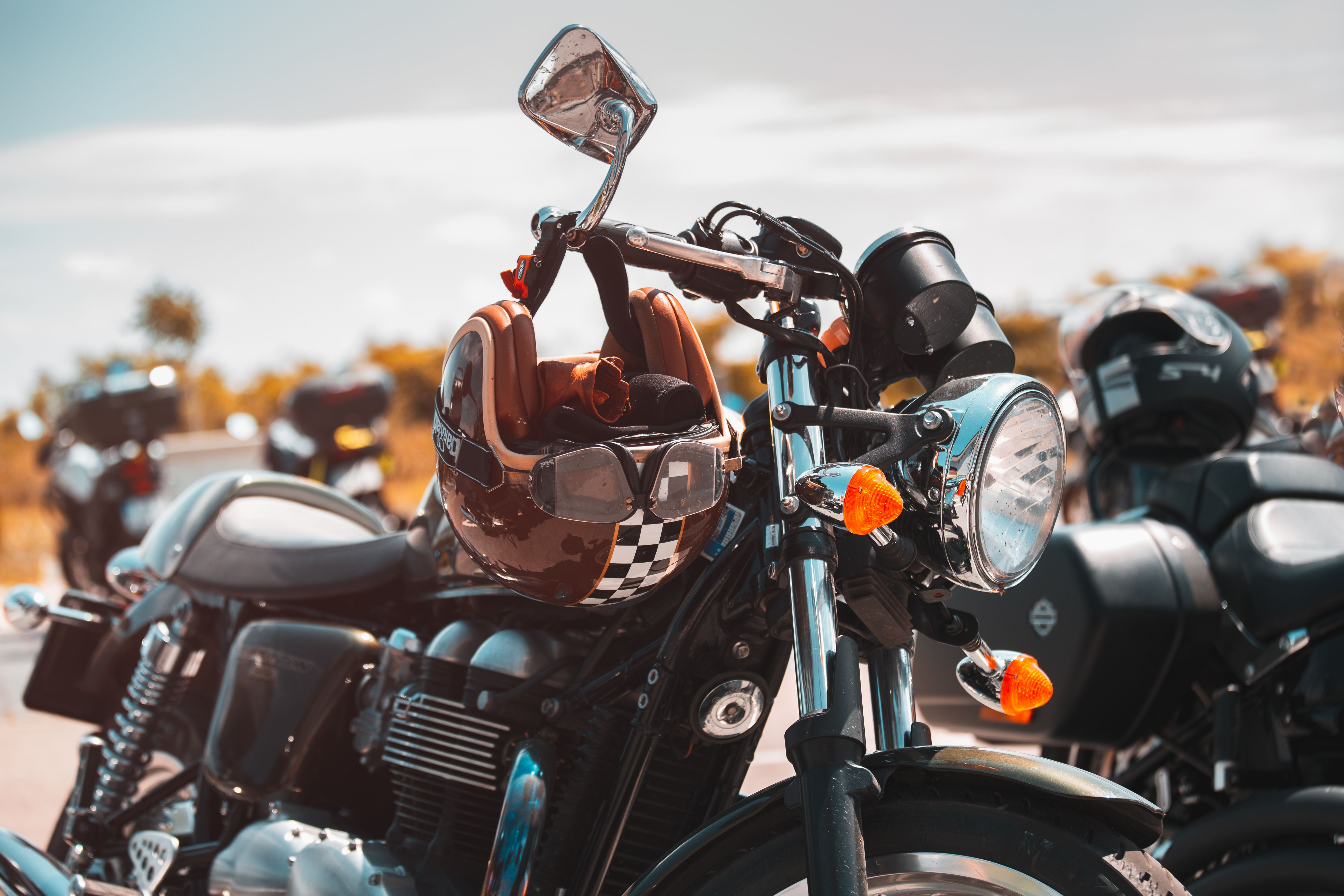 Close-up of a parked motorcycle with a helmet on the handlebar in a sunlit outdoor area.